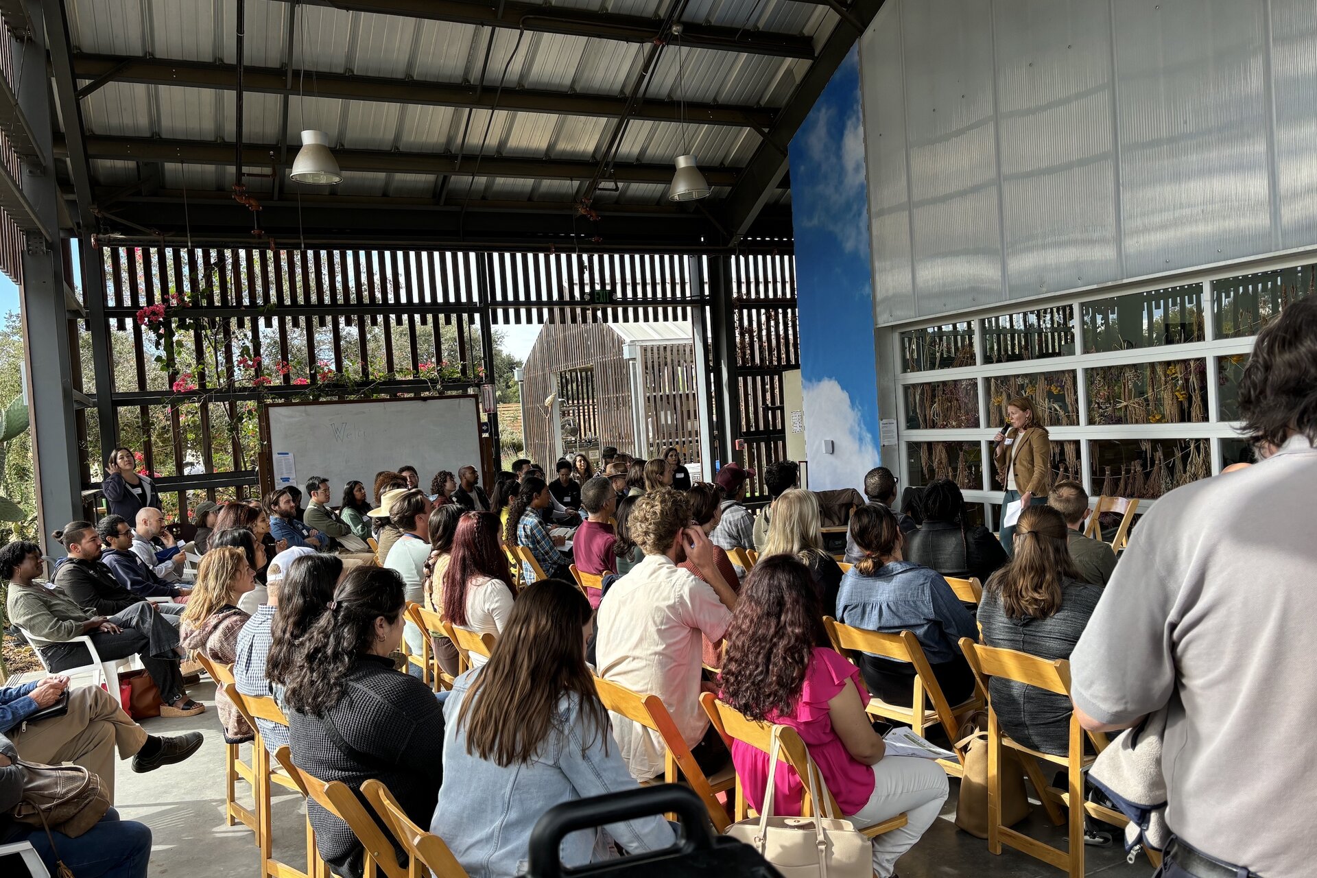 A group of people sitting in rows of chairs at an outdoor lecture
